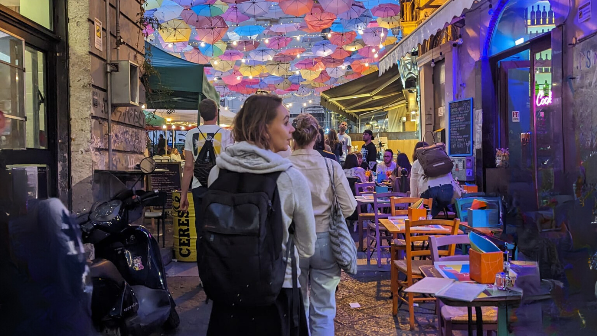 The One Life School - Your Why. Ali looks to the right as she walks under colourful umbrellas in